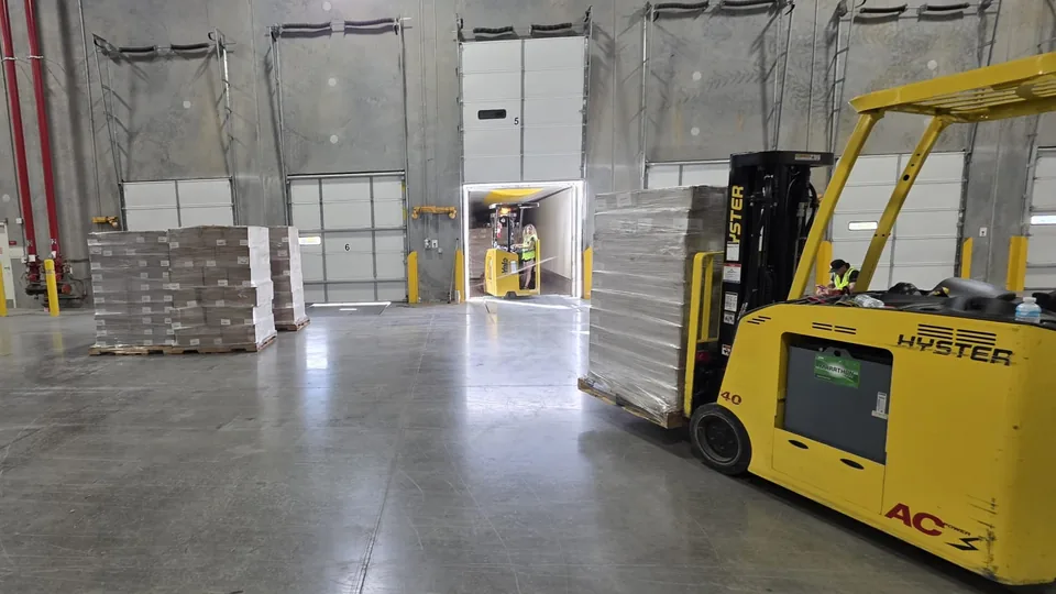 Forklift operator moving palletized freight in a warehouse
