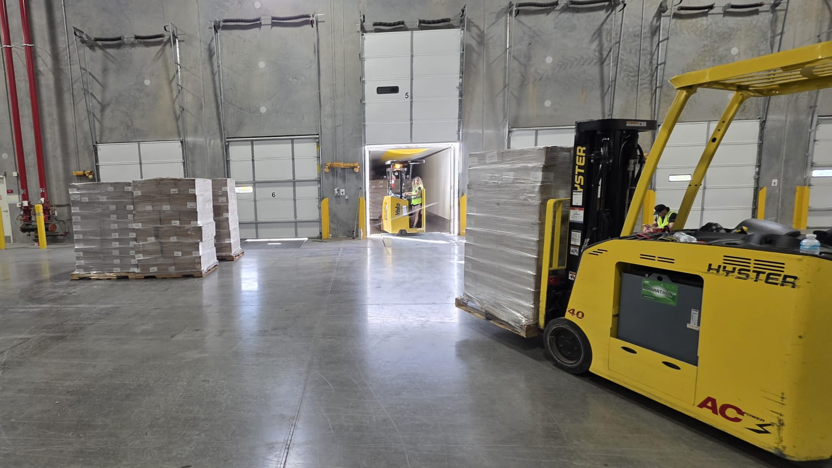 Certified forklift operator moving palletized freight at a warehouse dock